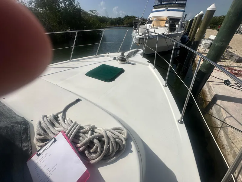 Slide: The Image of 1989 Bluewater 51' Coastal Cruiser docked, with coiled rope and clipboard on deck. - 5