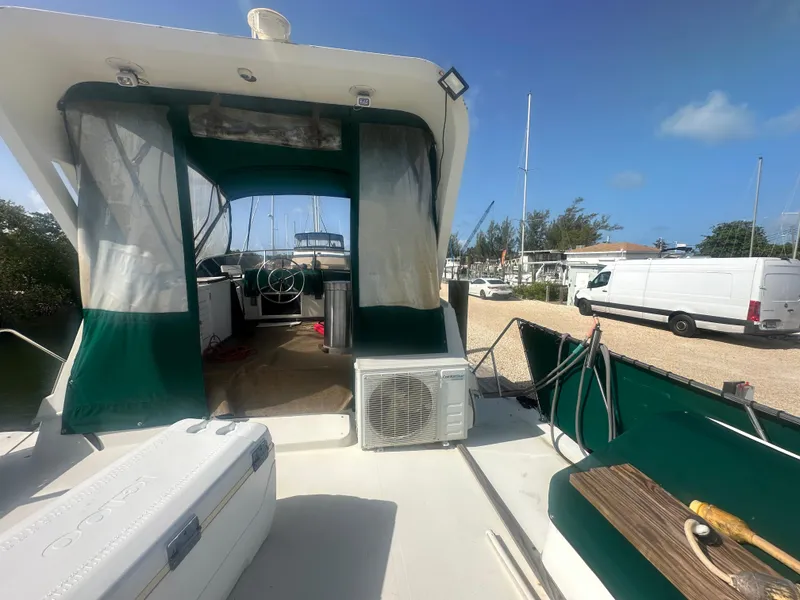 Slide: The Image of 1989 Bluewater 51' Coastal Cruiser with green canopy, docked under clear blue sky. - 9