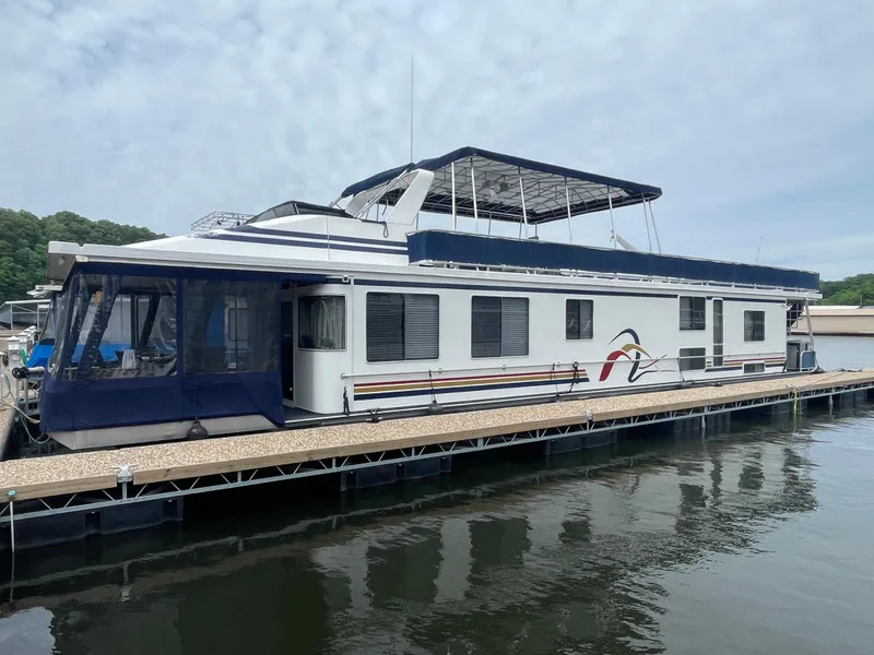 The Image of 2000 Funtime 16x72 houseboat docked on calm water, featuring a spacious upper deck. - 0