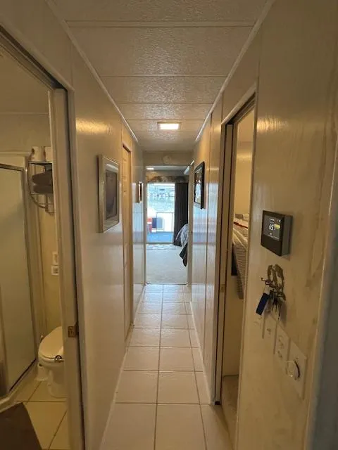 Slide: The Image of Narrow hallway inside a 2000 Funtime 16x72 houseboat, featuring tiled flooring and visible bathroom. - 8