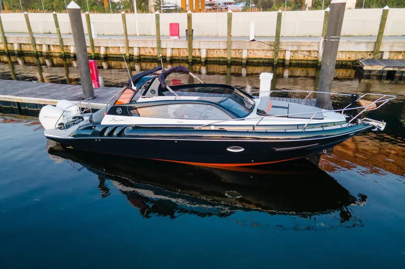 The Image of 2026 Hanover 305 Outboard boat docked on calm water, showcasing sleek design. - 0