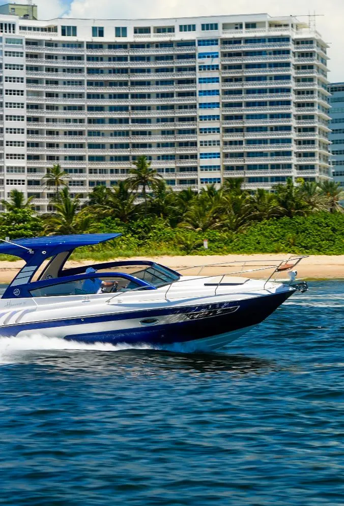 Slide: The Image of 2025 Hanover 305 Outboard cruising near a beachfront with modern high-rise buildings. - 17