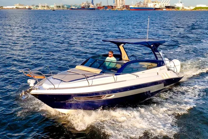 Slide: The Image of 2025 Hanover 305 Outboard cruising on open water with cityscape background. - 2