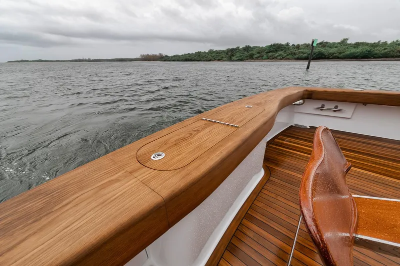 Slide: The Image of Jim Smith 2011 Custom Sportfish boat with wooden deck and chair on a cloudy day. - 11