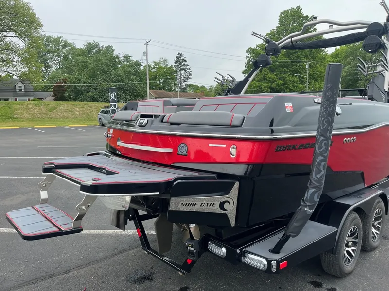 Slide: The Image of 2022 Malibu Wakesetter 23 LSV boat, red and black, parked on a trailer in a lot. - 5