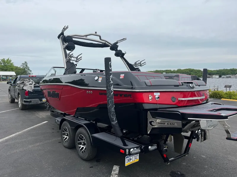 Slide: The Image of 2022 Malibu Wakesetter 23 LSV boat on trailer, parked near a lake. - 6