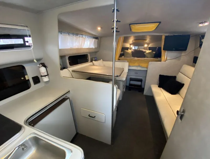 Slide: The Image of 1987 Chris-Craft 320 Amerosport interior with seating, kitchenette, and cozy sleeping area. - 23