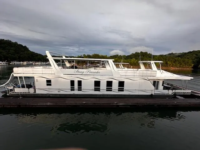 The Image of 2007 Sharpe 18 x 85 houseboat docked on a serene lake with lush greenery. - 0