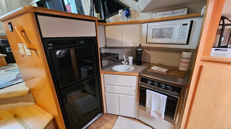 Slide: The Image of 1995 Carver 355 Aft Cabin kitchen with fridge, stove, microwave, and sink. - 17