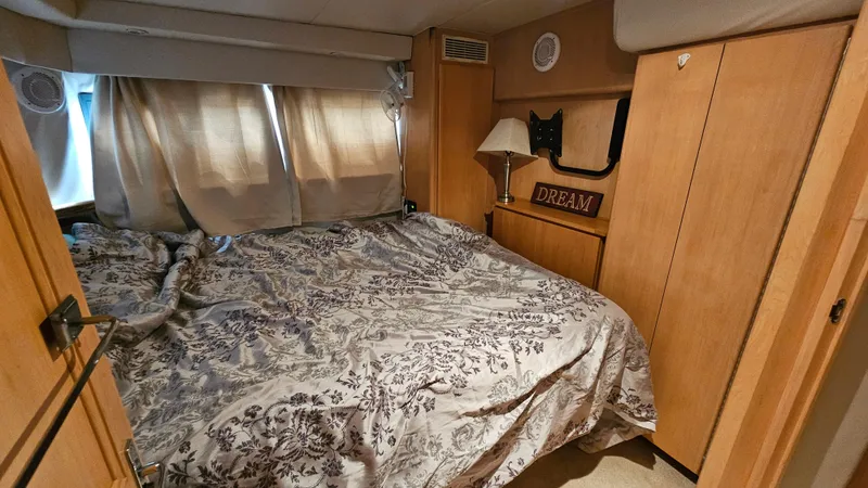 Slide: The Image of 1995 Carver 355 Aft Cabin bedroom with floral bedding and wooden cabinetry. - 24