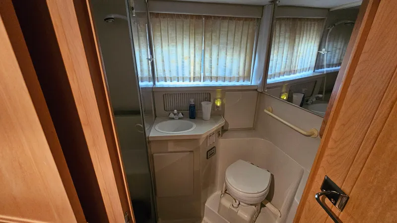Slide: The Image of 1995 Carver 355 Aft Cabin bathroom with sink, toilet, and window blinds. - 25