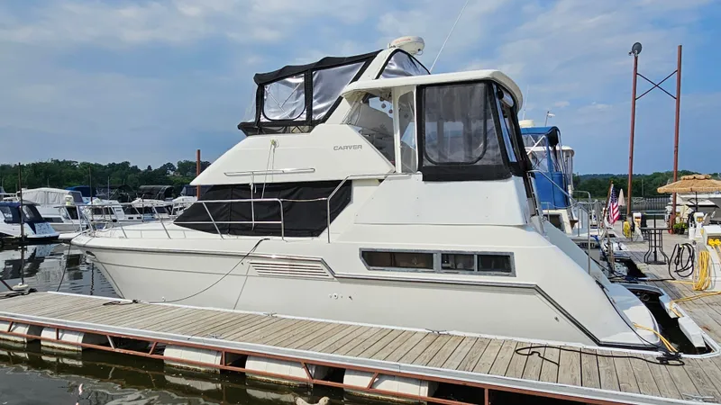 The Image of 1995 Carver 355 Aft Cabin yacht docked at marina under clear sky. - 1