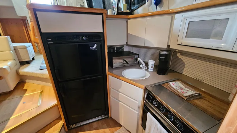 Slide: The Image of 1995 Carver 355 Aft Cabin kitchen with appliances, including fridge, microwave, and stove. - 18