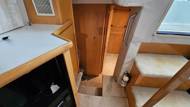 Slide: The Image of 1995 Carver 355 Aft Cabin interior with stairs, wood paneling, and carpeted flooring. - 22