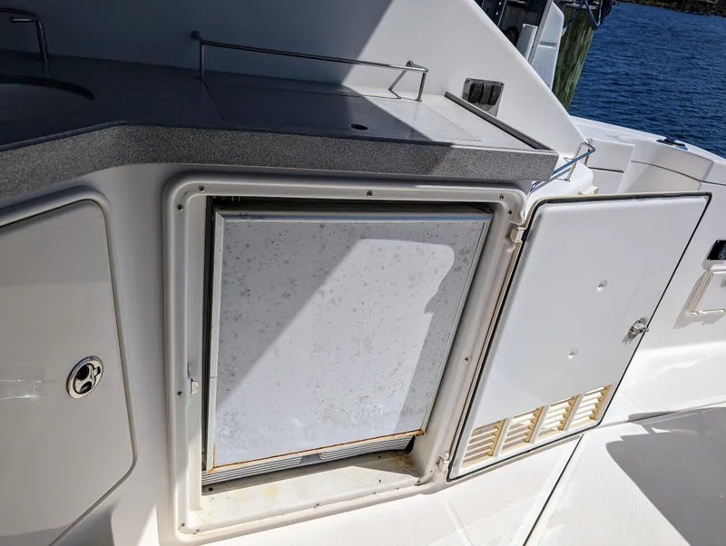 Slide: The Image of 2005 Regal 3560 yacht kitchenette with open storage compartment and countertop near water. - 10