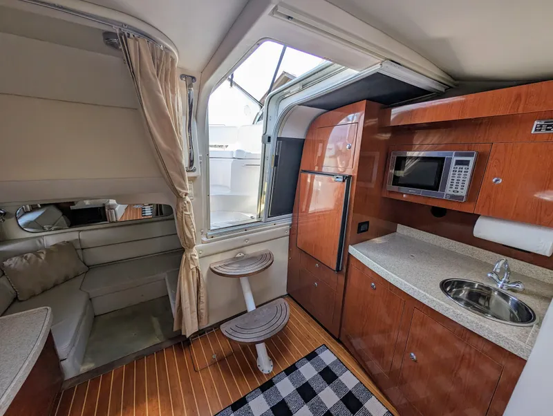 Slide: The Image of 2005 Regal 3560 yacht interior with kitchenette, seating area, and wooden flooring. - 19