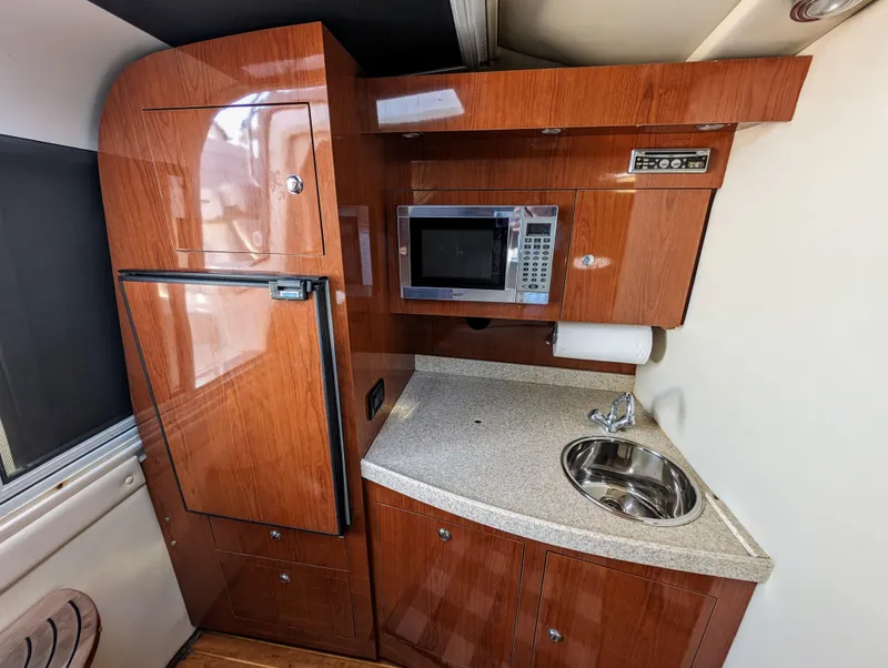 Slide: The Image of 2005 Regal 3560 yacht kitchen with wood cabinetry, microwave, sink, and compact fridge. - 20