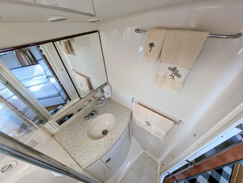 Slide: The Image of Bathroom interior of 2005 Regal 3560 yacht with sink, mirror, and palm-themed towels. - 33