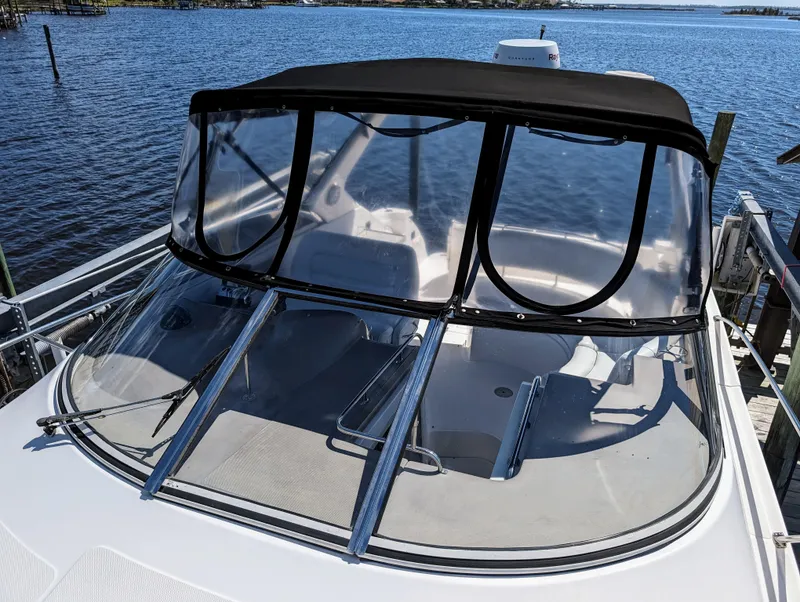 Slide: The Image of 2005 Regal 3560 boat docked by the water, featuring a clear canopy. - 36