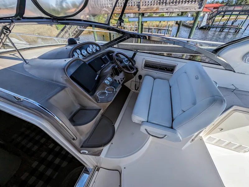 Slide: The Image of 2005 Regal 3560 boat cockpit with steering wheel, gauges, and white seating. - 5