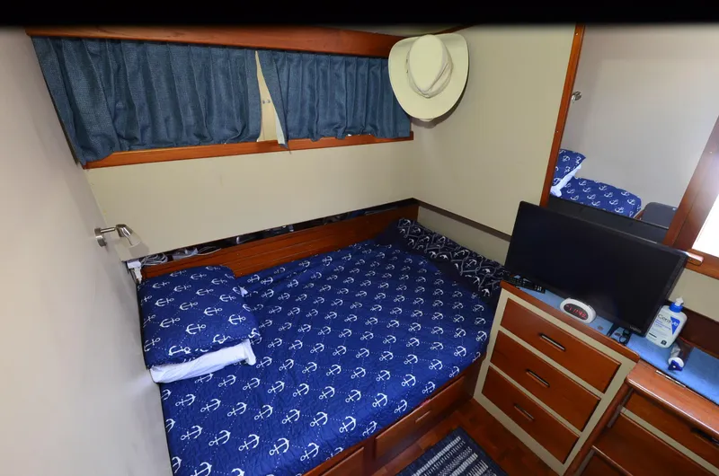 Slide: The Image of 1978 Grand Banks 36 Classic cabin with nautical bedding, TV, and hat on wall. - 16