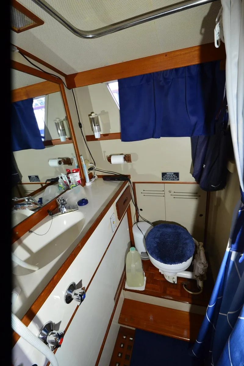 Slide: The Image of 1978 Grand Banks 36 Classic yacht bathroom with sink, toilet, and blue curtains. - 30