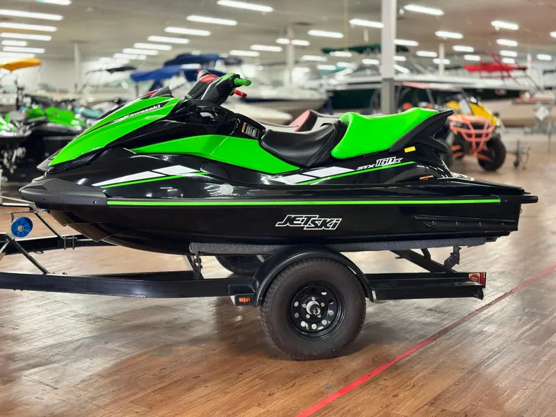 Slide: The Image of 2023 Kawasaki Jetski STX 160X in showroom, vibrant green and black design. - 2