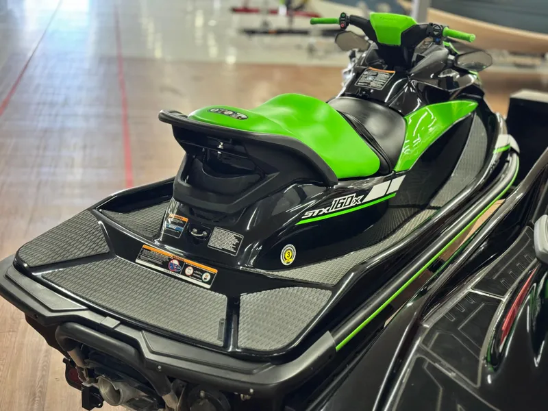 Slide: The Image of 2023 Kawasaki Jetski STX 160X in showroom, featuring sleek green and black design. - 5