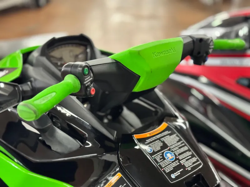 Slide: The Image of 2023 Kawasaki Jetski STX 160X handlebars, featuring vibrant green grips and control buttons. - 7