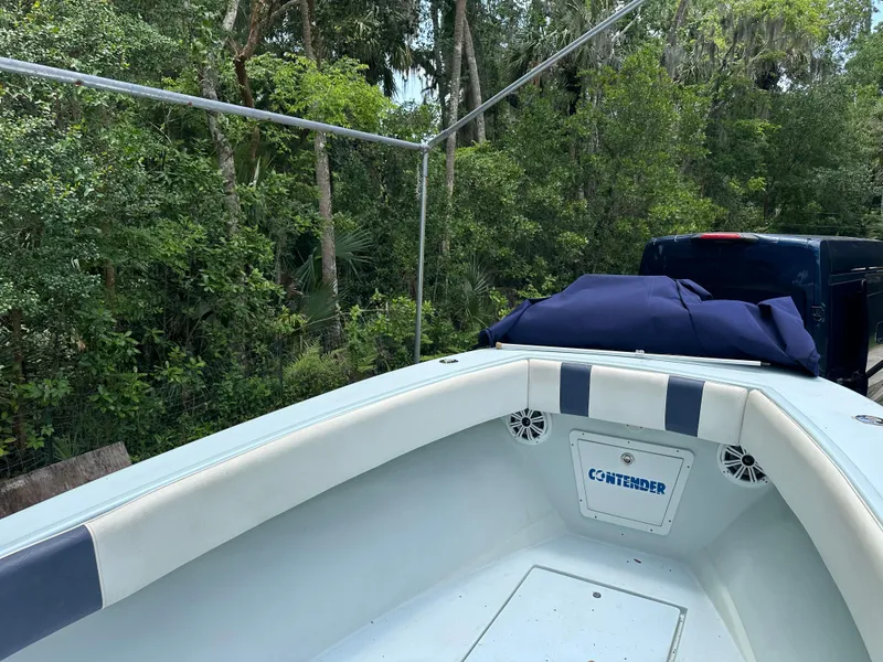 Slide: The Image of 1985 Contender 25 Classic boat with blue accents, parked near lush greenery. - 16