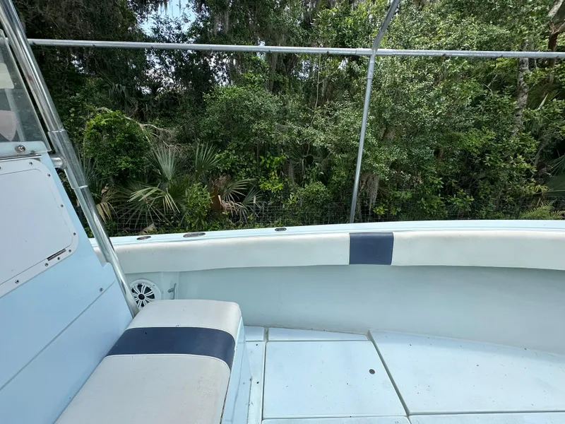 Slide: The Image of 1985 Contender 25 Classic boat interior with seating, surrounded by lush greenery. - 18