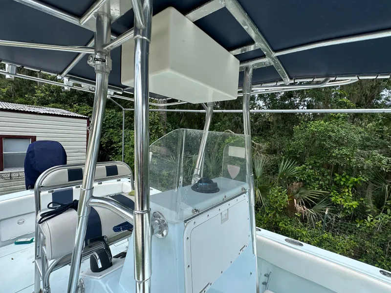 Slide: The Image of 1985 Contender 25 Classic boat interior with T-top and console, surrounded by lush greenery. - 23