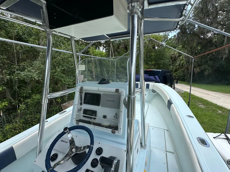 Slide: The Image of 1985 Contender 25 Classic boat cockpit with steering wheel and control panel, surrounded by lush greenery. - 25