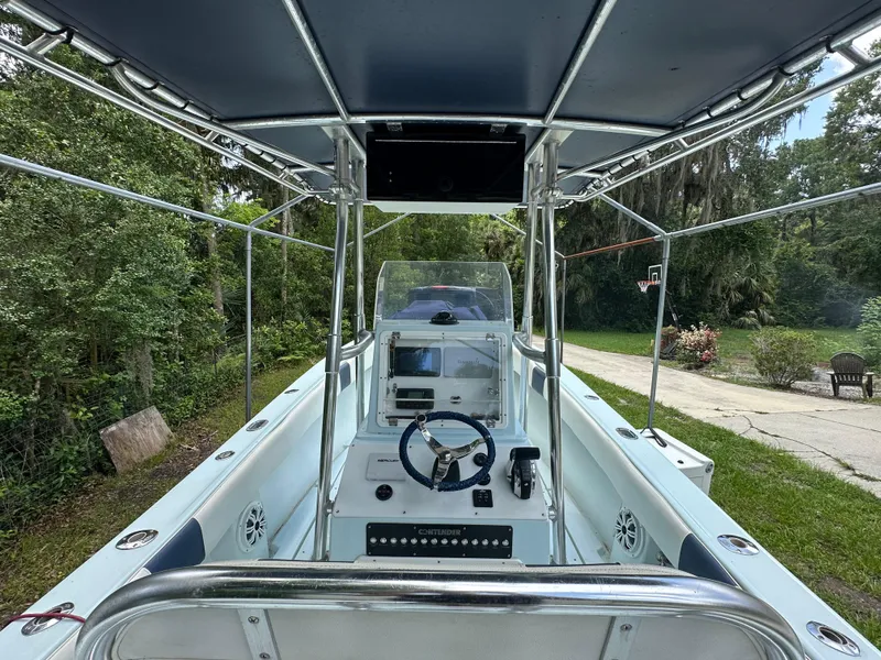 Slide: The Image of 1985 Contender 25 Classic boat interior with steering wheel and console, surrounded by lush greenery. - 26