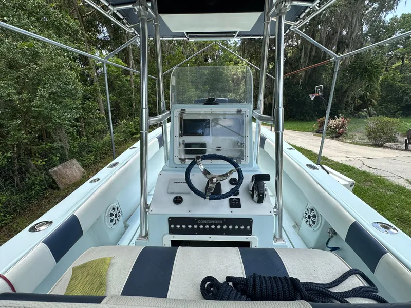 Slide: The Image of 1985 Contender 25 Classic boat interior with steering wheel and control panel, surrounded by greenery. - 27