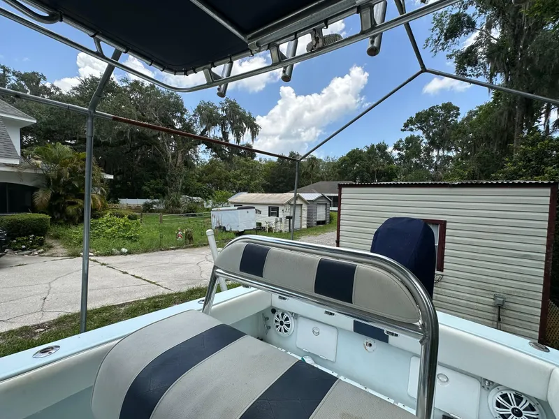 Slide: The Image of 1985 Contender 25 Classic boat with striped seating, parked outdoors near trees and buildings. - 35