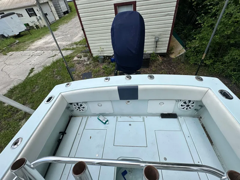Slide: The Image of 1985 Contender 25 Classic boat interior with rod holders and speakers, parked near a house. - 38