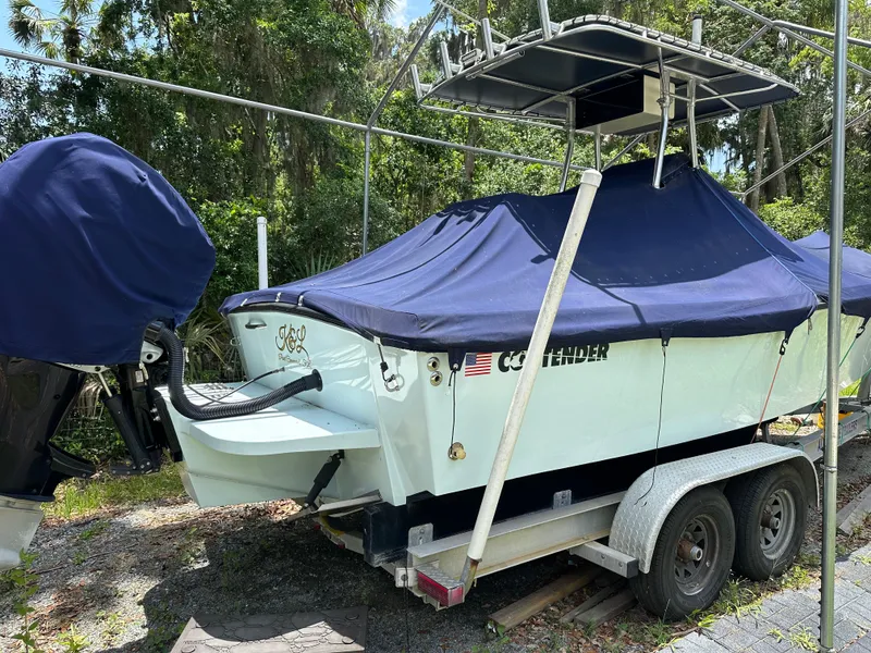 Slide: The Image of 1985 Contender 25 Classic boat on trailer, covered, with outboard motor, parked outdoors. - 4
