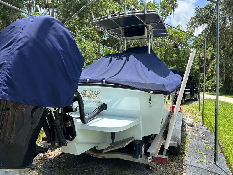 Slide: The Image of 1985 Contender 25 Classic boat on trailer, covered, with outboard motor, parked outdoors. - 5