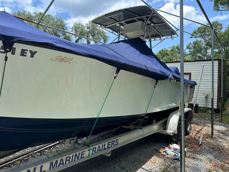 Slide: The Image of 1985 Contender 25 Classic boat on trailer, covered with blue tarp, outdoors. - 8