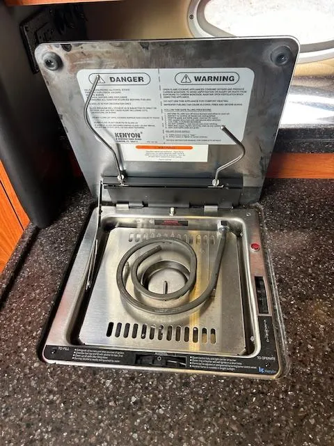 Slide: The Image of Electric stove in 2013 Rinker 290 Express Cruiser galley, featuring safety warnings. - 27