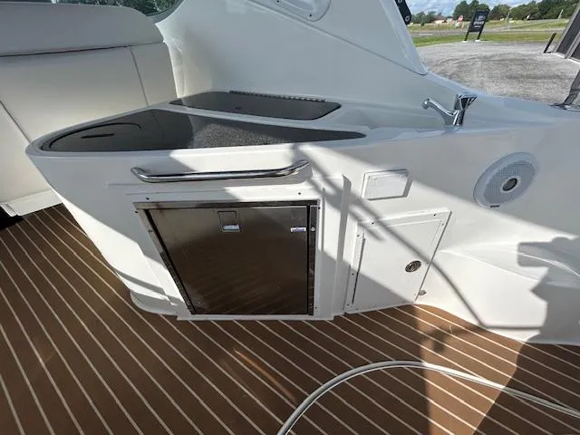 Slide: The Image of 2013 Rinker 290 Express Cruiser interior with kitchenette and wood-patterned flooring. - 37