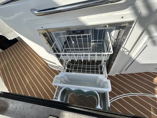 Slide: The Image of Open drawer on 2013 Rinker 290 Express Cruiser, showcasing storage space and deck flooring. - 38