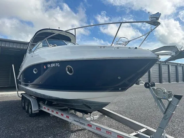 Slide: The Image of 2013 Rinker 290 Express Cruiser on trailer, parked outdoors under cloudy sky. - 4