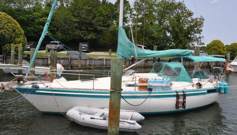 The Image of 1986 Scanmar 33 sailboat docked with turquoise covers and a small dinghy alongside. - 1
