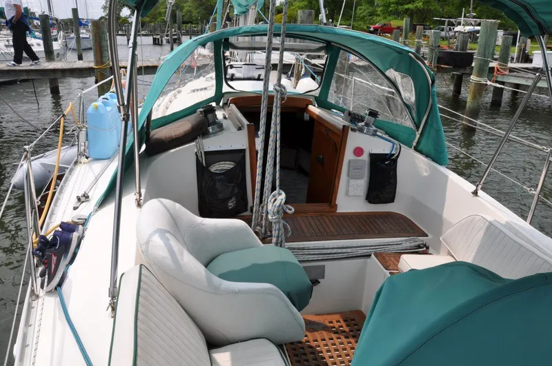Slide: The Image of 1986 Scanmar 33 sailboat cockpit with green canopy and seating at marina. - 11
