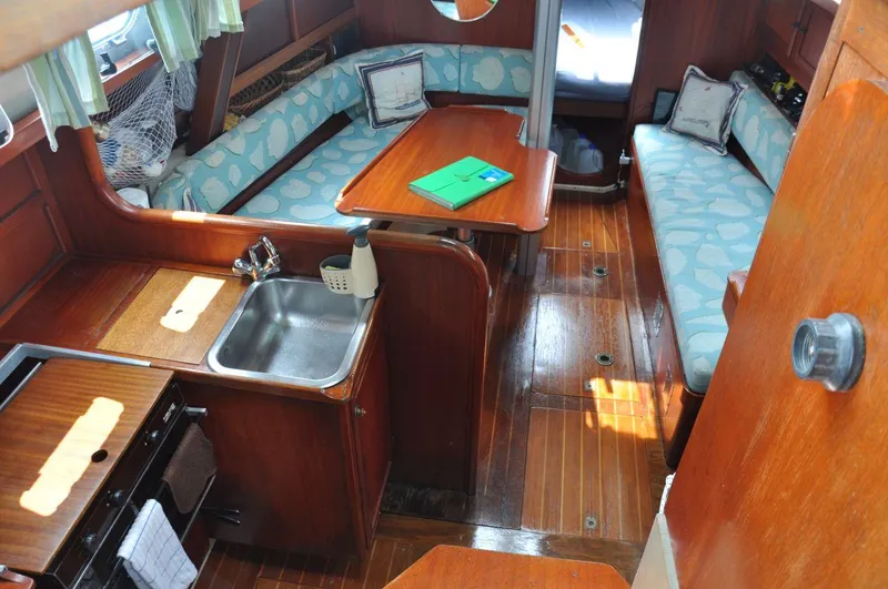 Slide: The Image of 1986 Scanmar 33 yacht interior with wooden finish, kitchenette, and cozy seating area. - 15