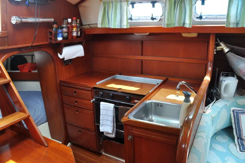 Slide: The Image of Interior of 1986 Scanmar 33 sailboat with wooden cabinetry and compact kitchen area. - 16