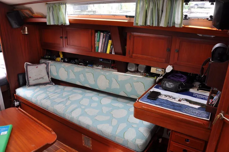 Slide: The Image of 1986 Scanmar 33 yacht interior with wooden cabinets, cushioned seating, and bookshelves. - 18