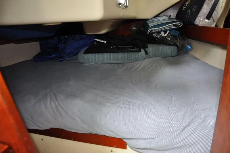 Slide: The Image of Cozy cabin berth in a 1986 Scanmar 33 sailboat, featuring bedding and storage. - 21